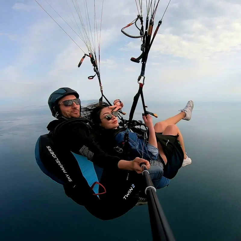 Deniz üzerinde tandem uçuş yapan pilot ve gülümseyen yolcu